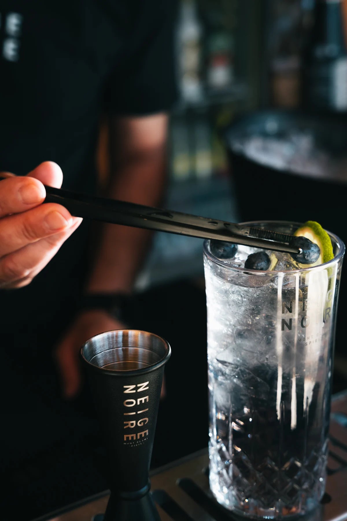 Preparing a Neige Noire cocktail with a jigger and glass